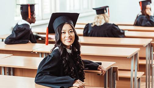 Student in graduation attire in the classroom